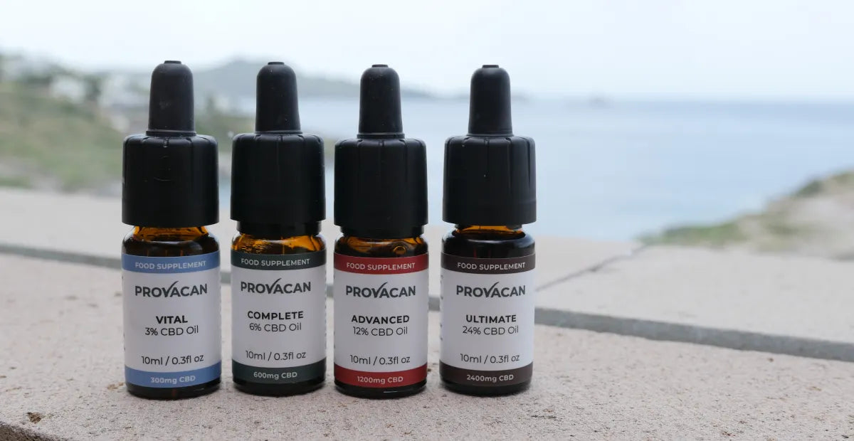 Full range of four Provacan CBD oil bottles next to a beach