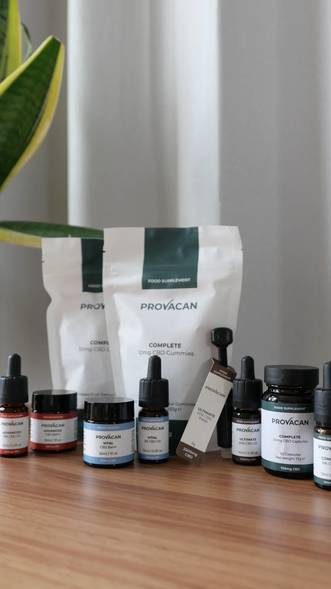Collection of Provacan CBD products on a wooden desk (capsules, balms, gummies, oils)