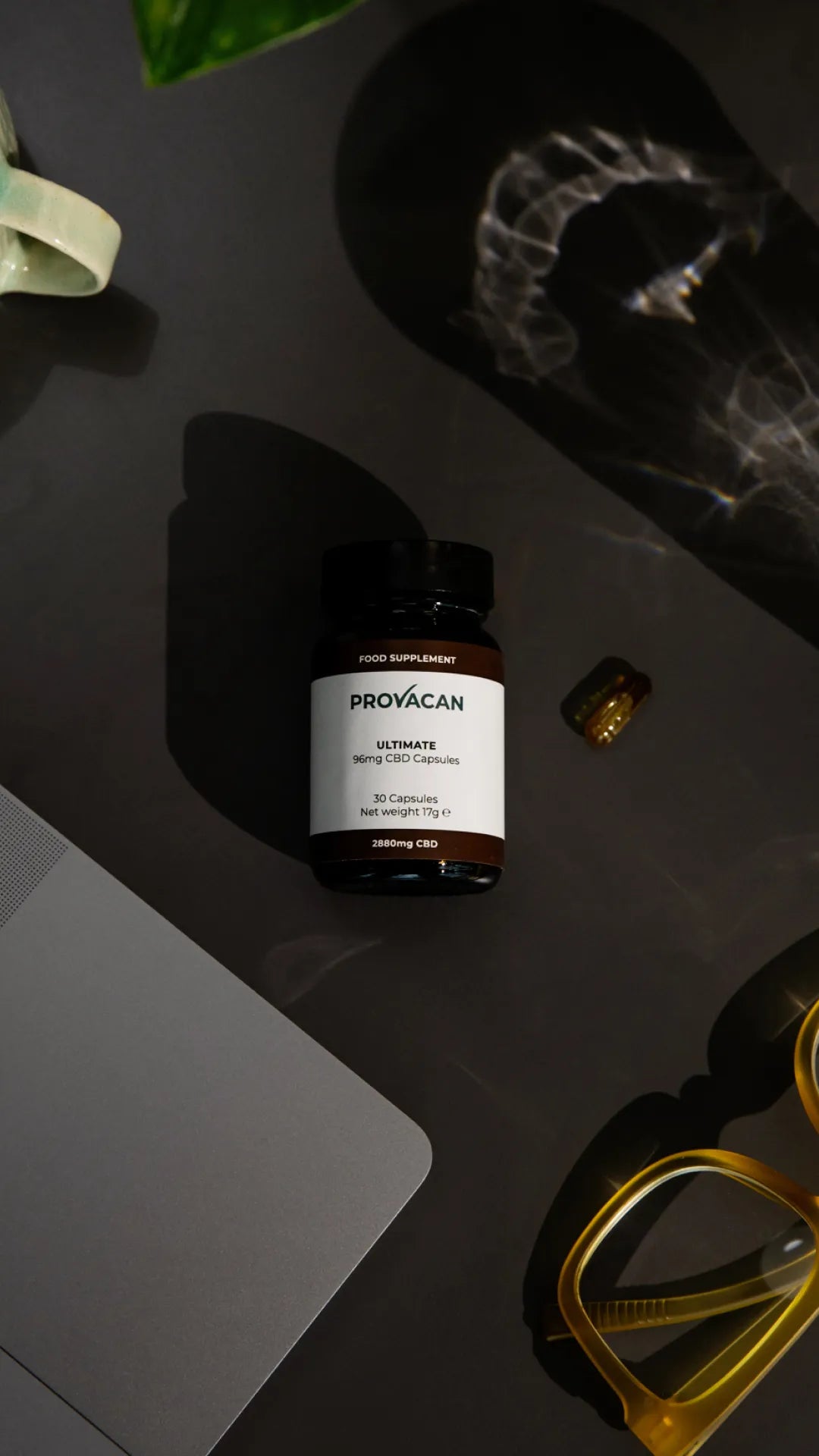 CBD capsules from Provacan: Ultimate 96mg CBD capsules on a grey desk next to a laptop