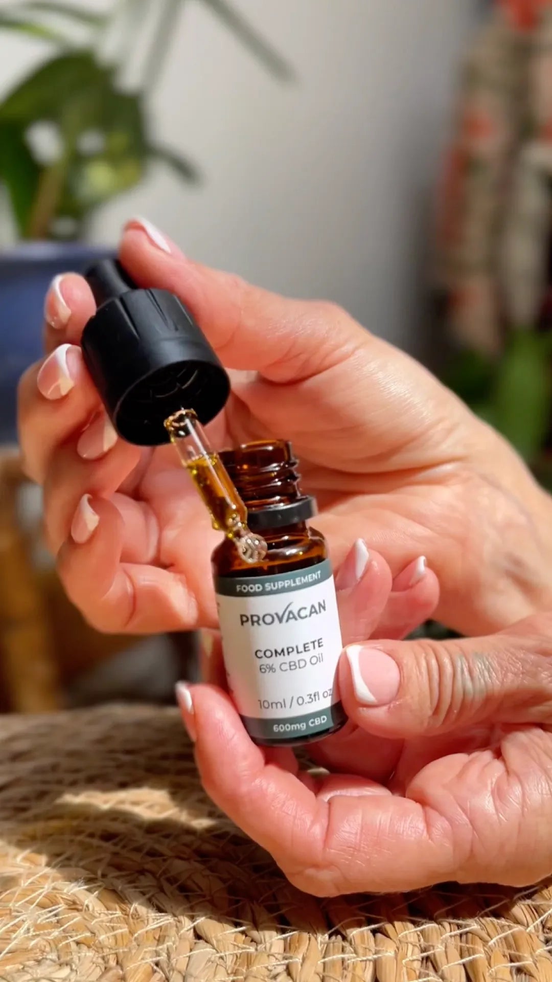 Woman's hands holding a bottle of Provacan Complete 6% 600mg CBD oil and its dropper
