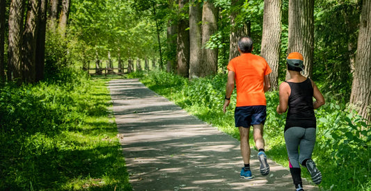 Two people jogging on a path through a forest