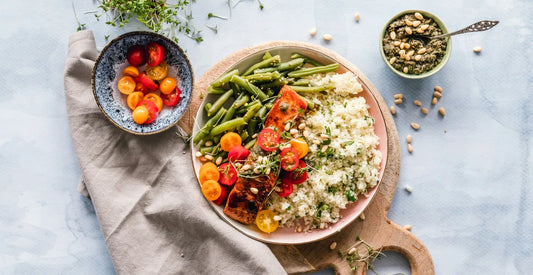 Healthy salmon bowl with green beans, cauliflower rice, cherry tomatoes and pesto on a light background
