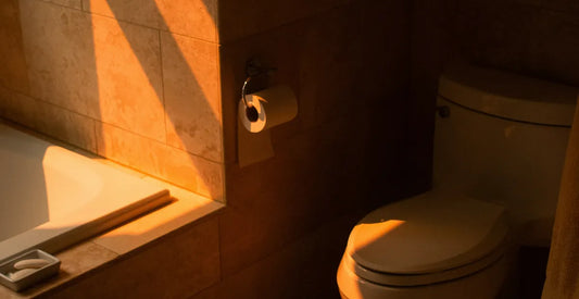 Bathroom scene with a toilet and tiled wall, illuminated by warm light