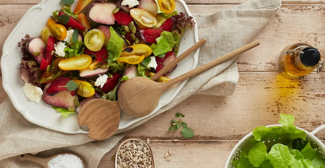 Colourful salad with wooden spoons on a rustic wooden table