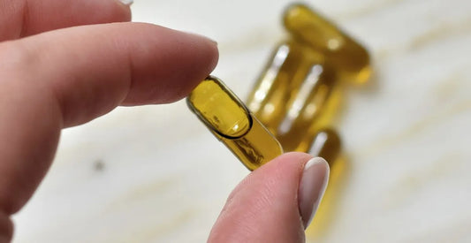 Hand holding a golden Provacan CBD oil capsule supplement
