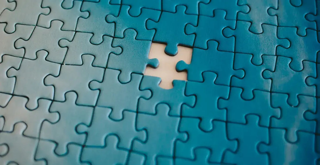 Close-up of a blue jigsaw puzzle with a single missing piece in the center