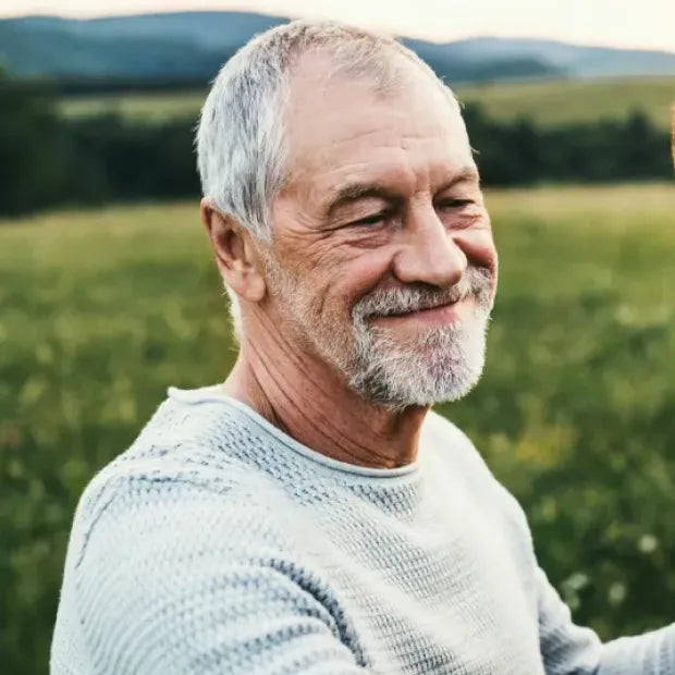 Man with a beard and gray hair standing in a field