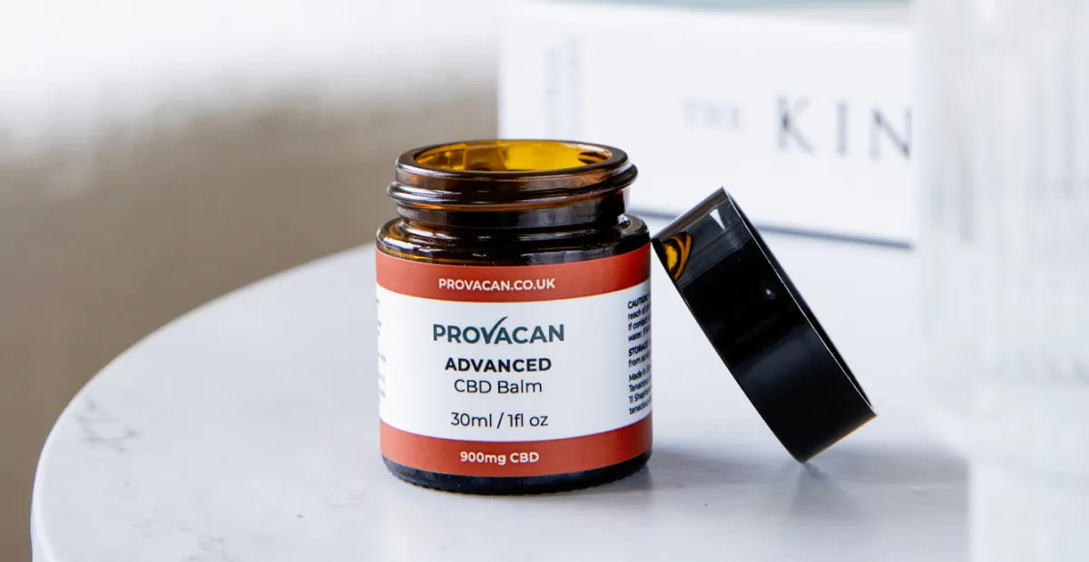 Brown jar of Provacan Advanced CBD Balm on a white surface with a blurred background