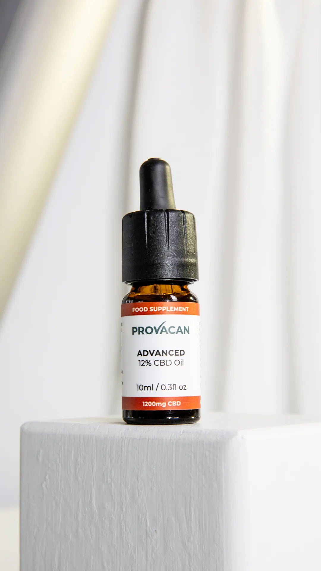 Bottle of Provacan Advanced CBD oil on a white surface with a white curtain background