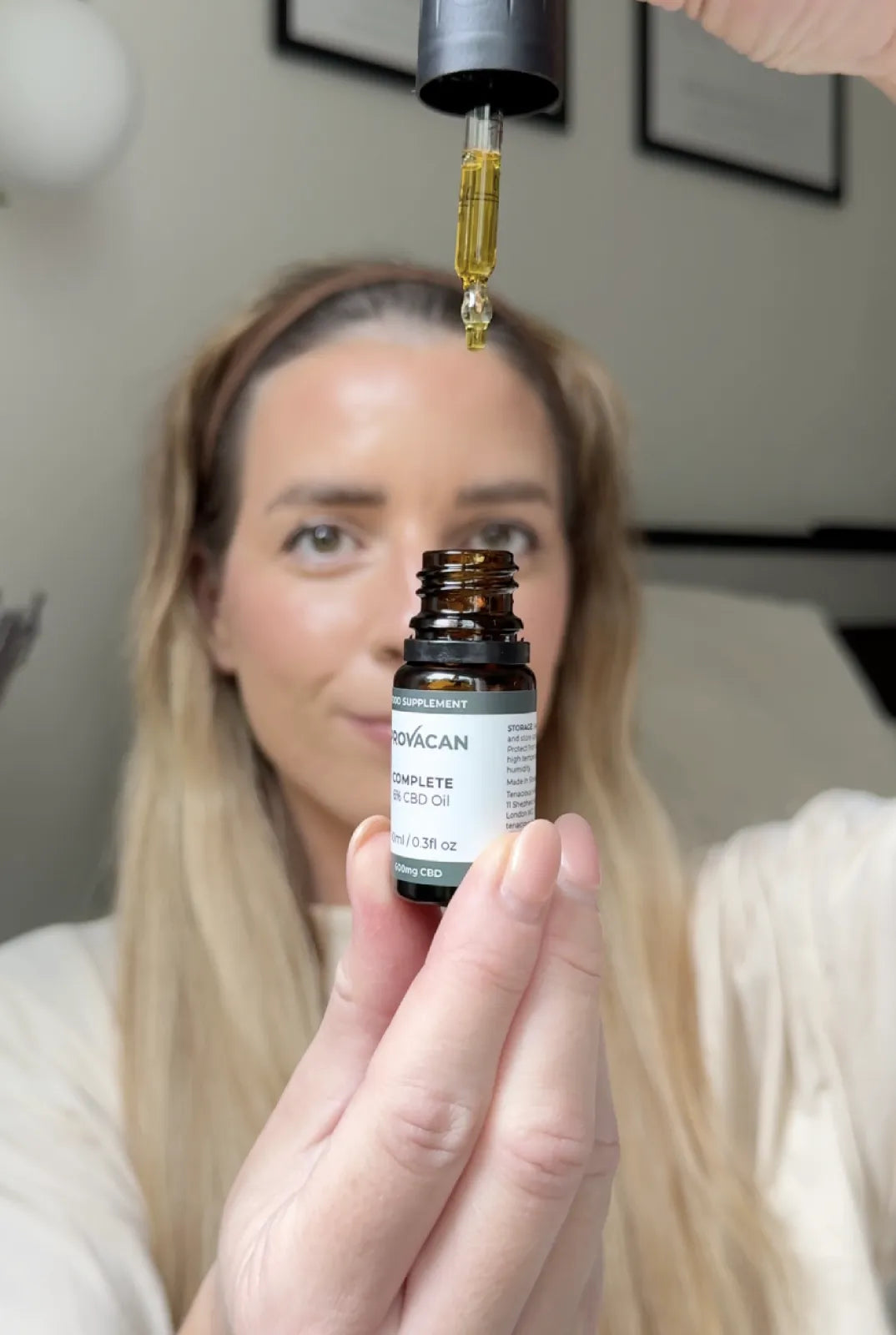 Woman holding a bottle of Provacan Complete 600mg CBD oil with a dropper above it