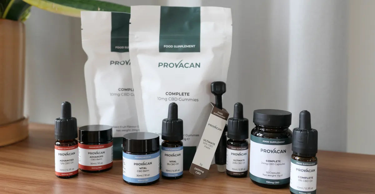 Range of Provacan CBD products on a wooden surface with a neutral background: CBD oil, CBD balm, CBD gummies, CBD capsules and CBD paste