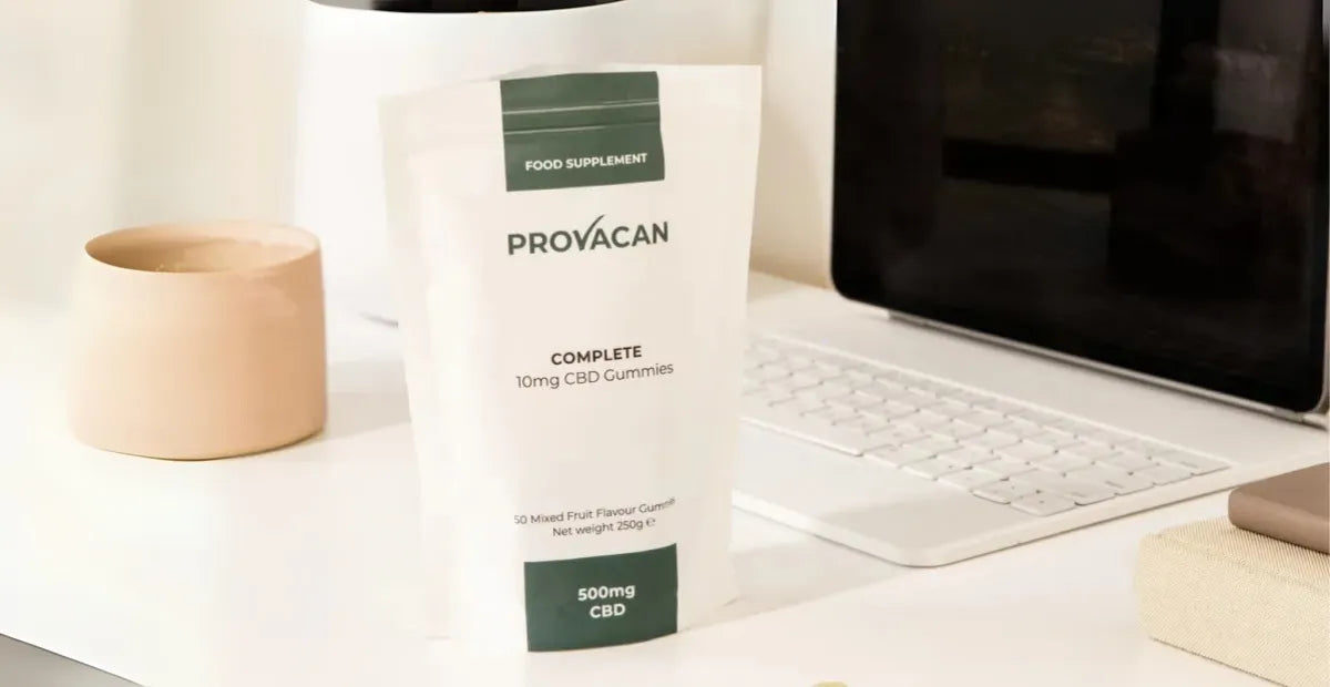 Bag of Provacan Complete CBD Gummies 10mg on a desk next to a computer