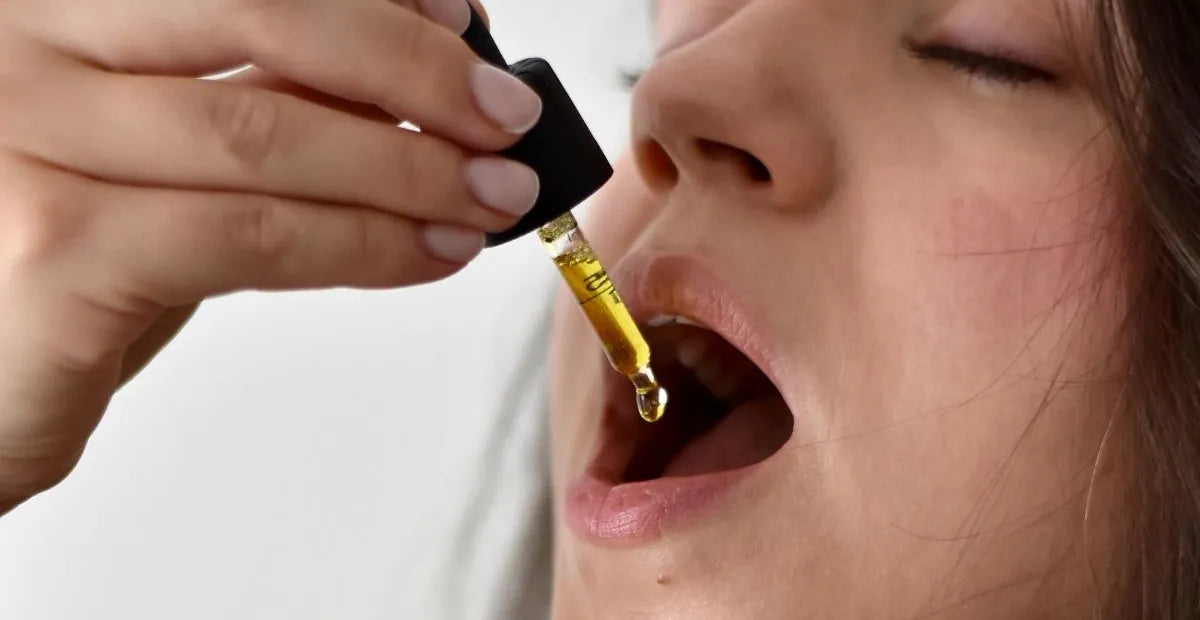 Woman closing her eyes taking some CBD oil with a dropper in her mouth
