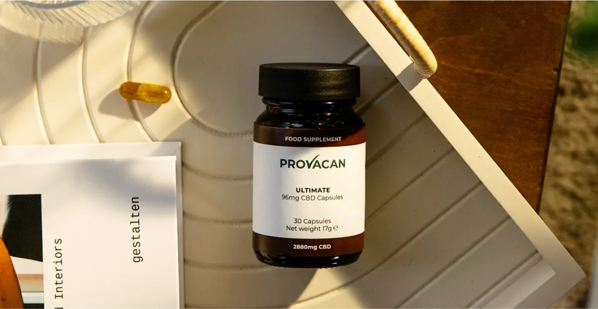 Provacan premium CBD Ultimate capsules 96mg bottle on a wooden tray next to a book