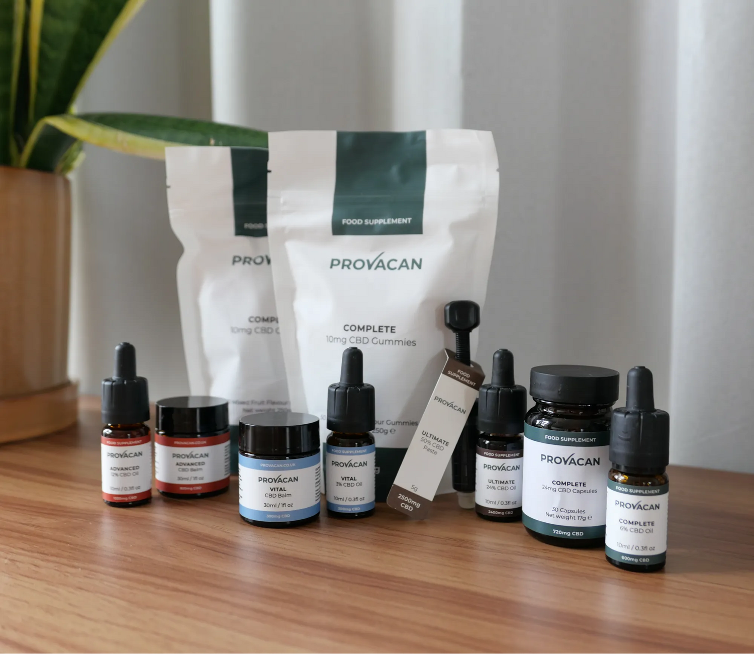 Provacan CBD Product range of Oils, Balms, Gummies, Paste and Capsules on a wooden table