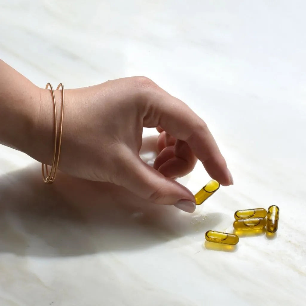 A person holding one CBD oil capsule. 