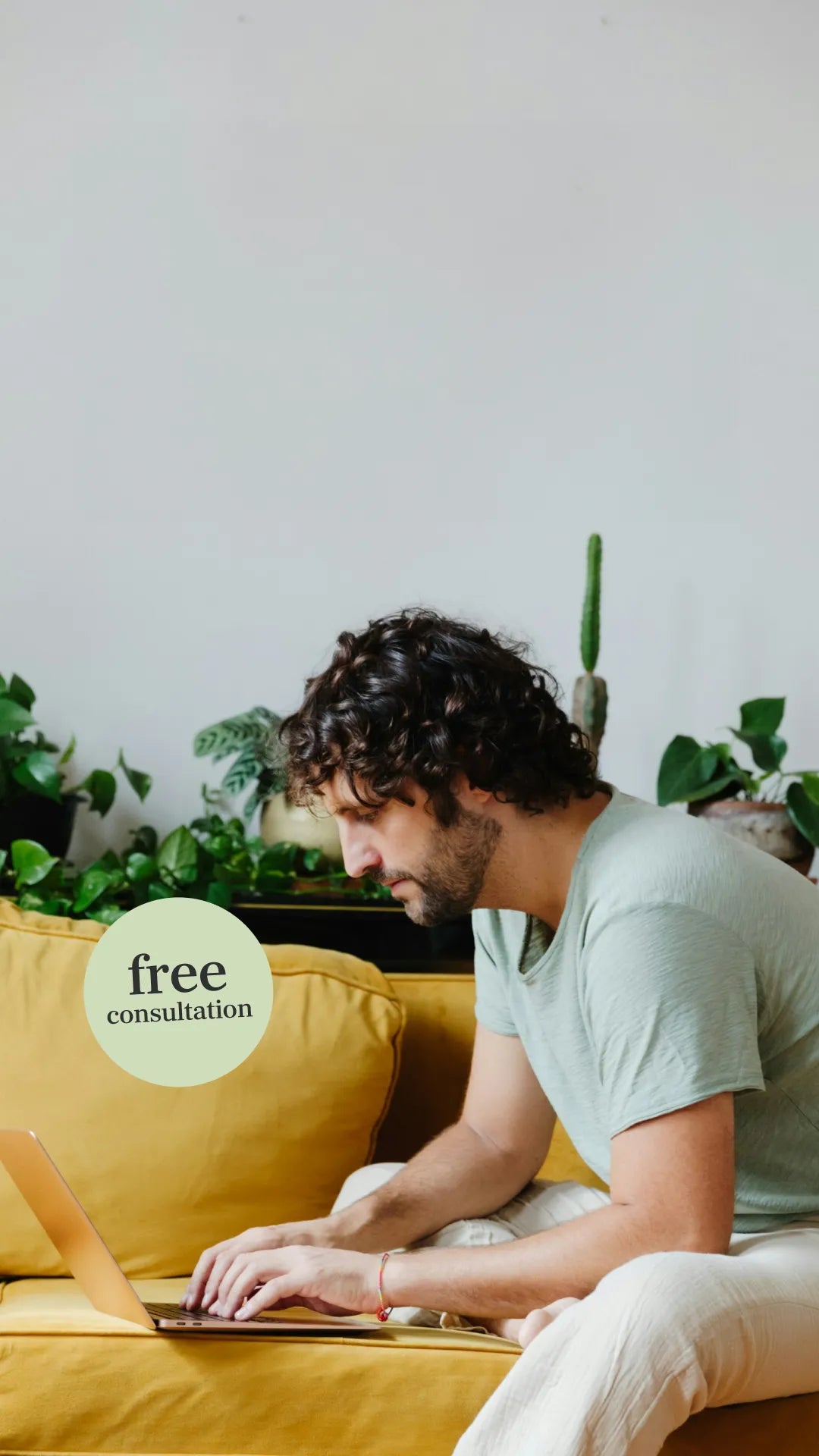 Man sitting on a couch typing on a laptop with a pale green roundel icon written 'Free consultation'