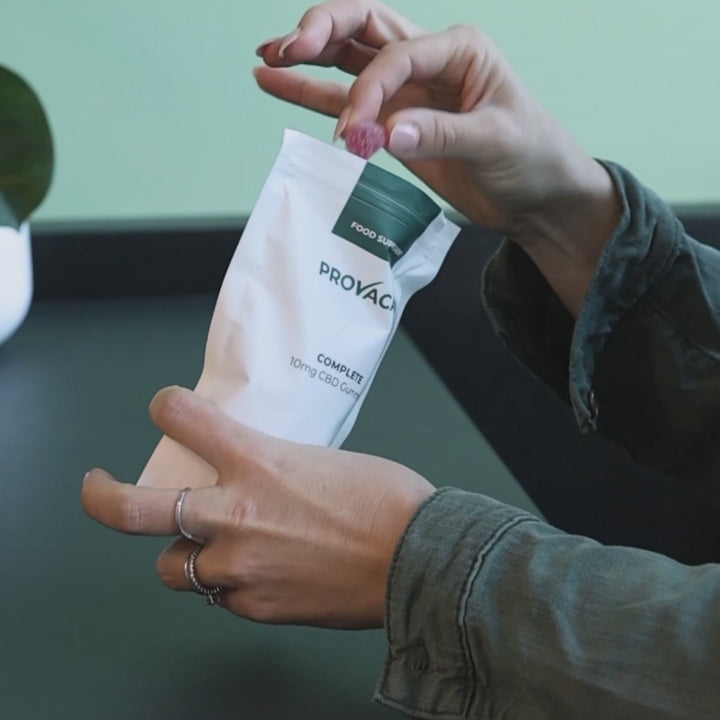 A close-up shot of a pack of CBD Gummies on a kitchen counter with a few gummies next to it. The next shot shows a person taking a gummy out of the pack and a close-up of red gummy follows. 